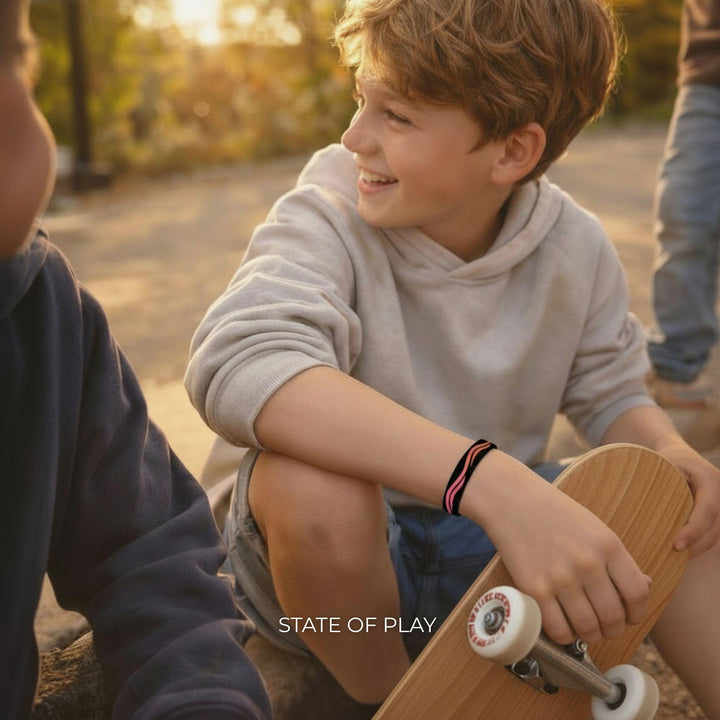 Kind sitzt mit Skateboard im Abendlicht und trägt das Calways Sun Flow Armband am Handgelenk.